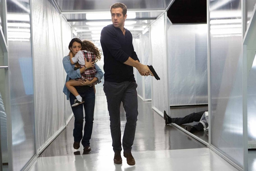 Madeline (Natalie Martinez) holds a child and follows an armed Damian (Ryan Reynolds) in Self/Less (2015).