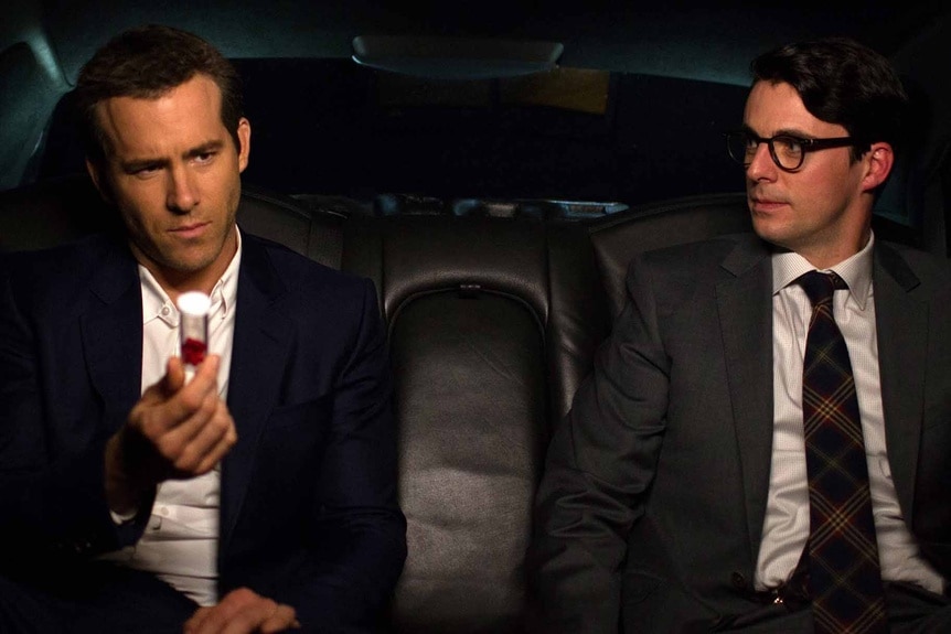 Damian (Ryan Reynolds) holds a vial next to Albright (Matthew Goode) in the back of a car in Self/Less (2015).