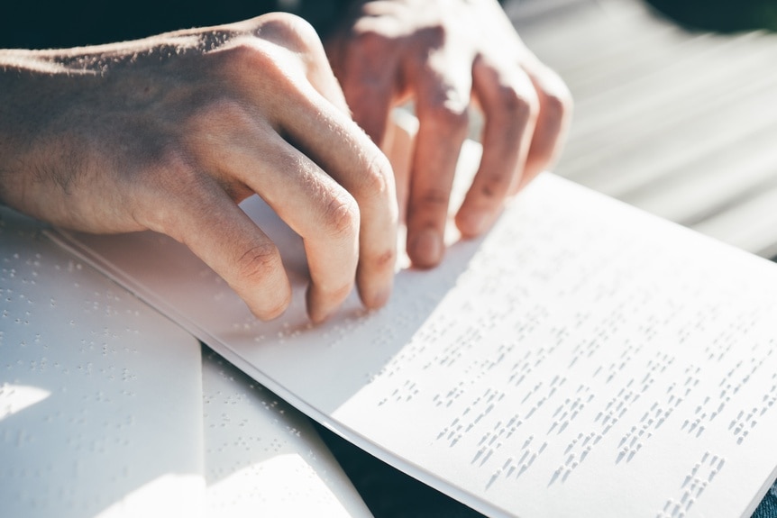 A closeup of hands reading braille.