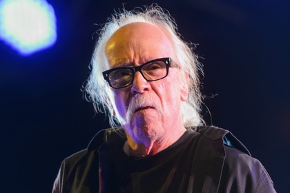 John Carpenter wears his signature black glasses.