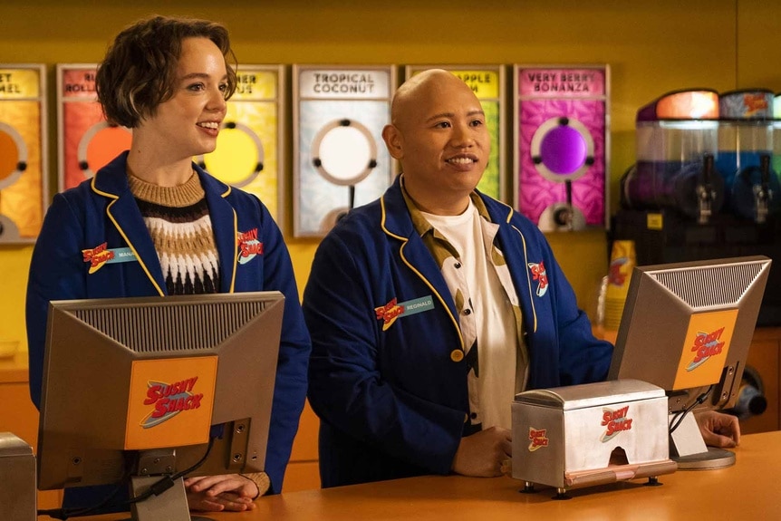 Sarah Kinney (Em Haine) and Reginald (Jacob Batalon) work at a movie snack counter in Reginald the Vampire Episode 201.