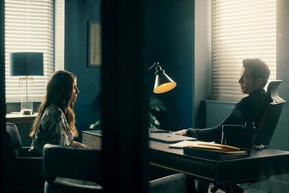 (l-r) Susan Ireland (Sarah Levy) and Luke Roman (Tim Rozon) speak over a desk in SurrealEstate 201 "Trust the Process".