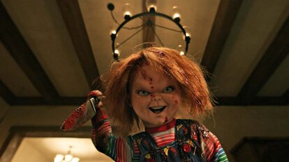 Chucky smiles murderously while holding a bloody knife in Chucky 303.